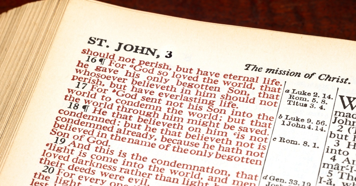 Close-up of a Bible page showing the verses John 3:16-19 in their entirety and parts of other verses. Jesus's words are in red.