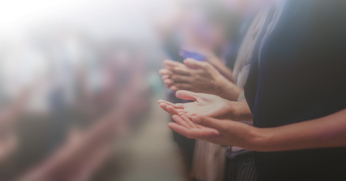 How To Get the Most out of Listening to a Sermon A close-up of a row of people in church, standing with their forearms parellel to the floor and their palms facing upward.