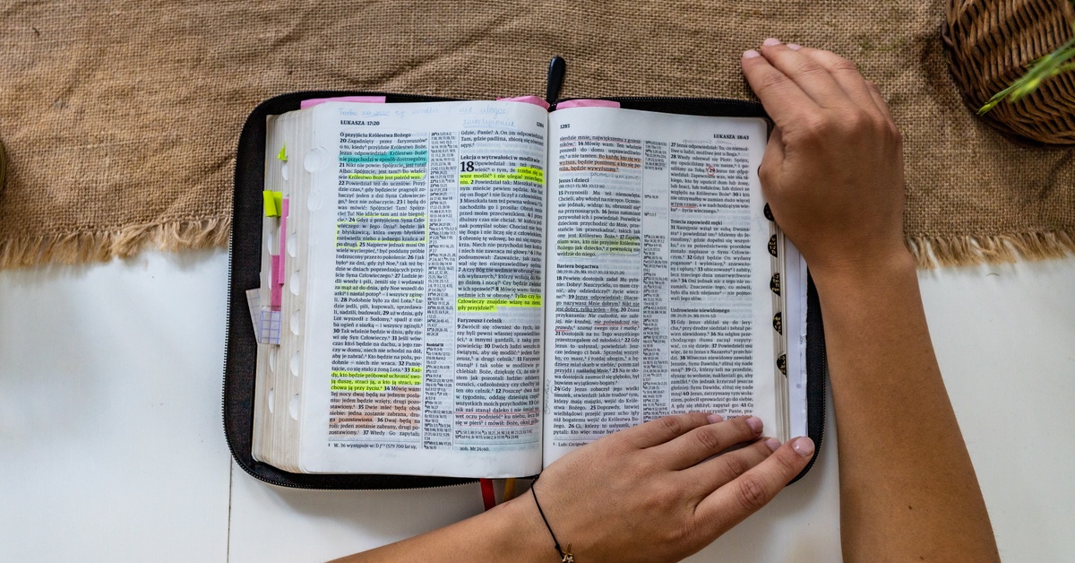 Understanding the Different Genres in the Bible A Bible features colorful highlights marking verses and tabs protruding from its pages. A person begins to turn a page.