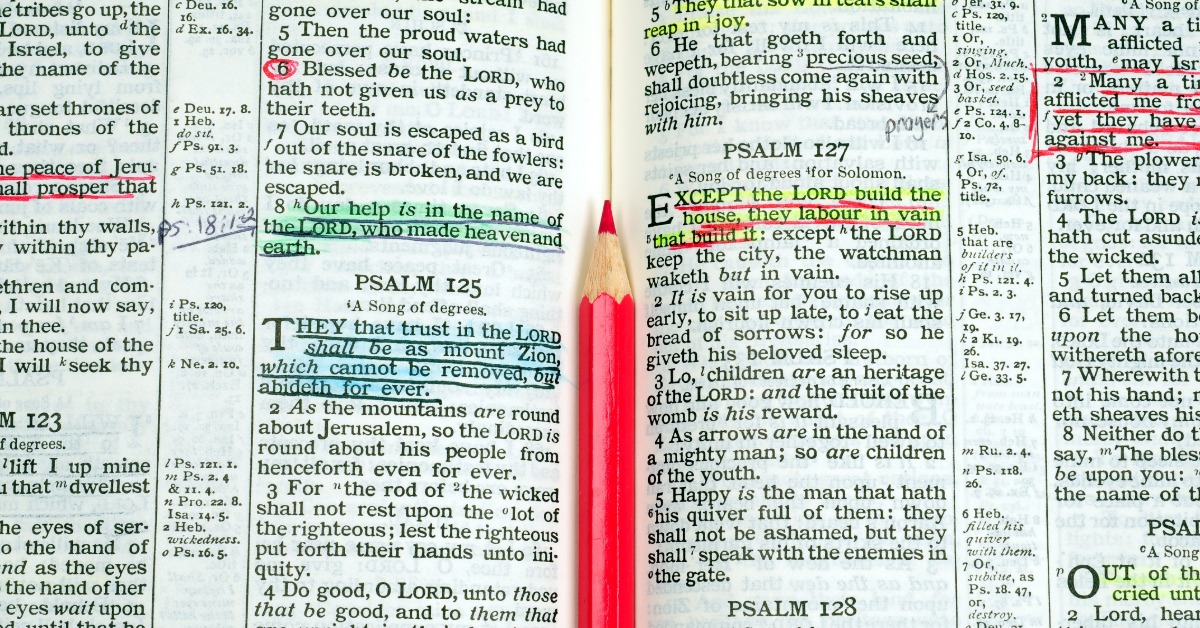 An open Bible shows Psalms with verses highlighted and underlined in various colors. A red pencil is between the pages.