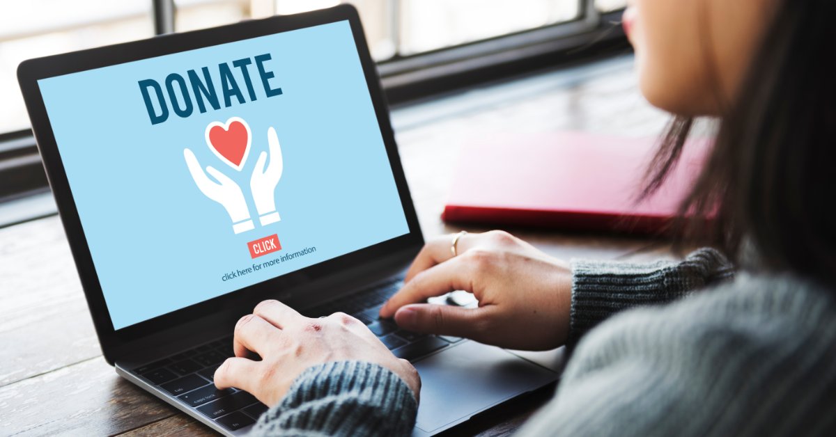 8 Ways To Worship God in Your Everyday Life A person sits at a laptop. The screen shows a blue donation page with a heart-and-hands icon under the word "Donate."